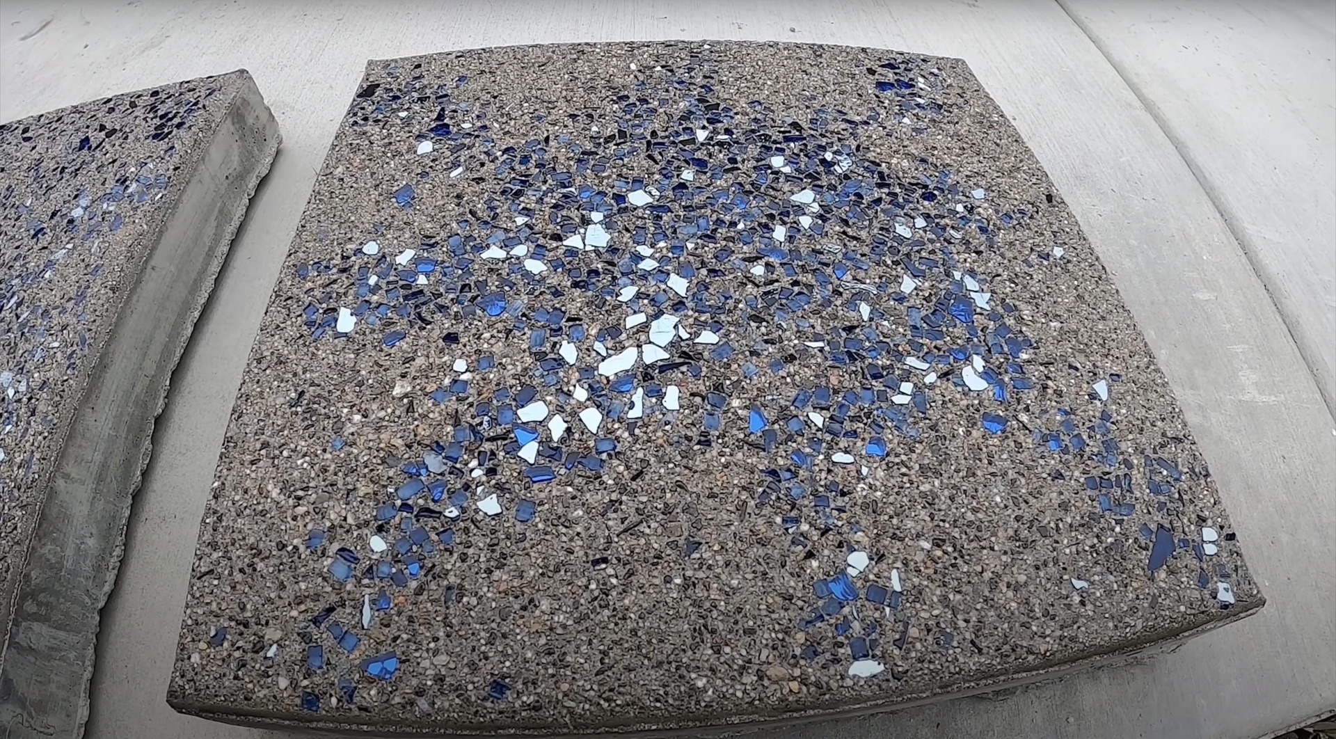 Exposed aggregate concrete sample showing decorative concrete finish with blue glass accents